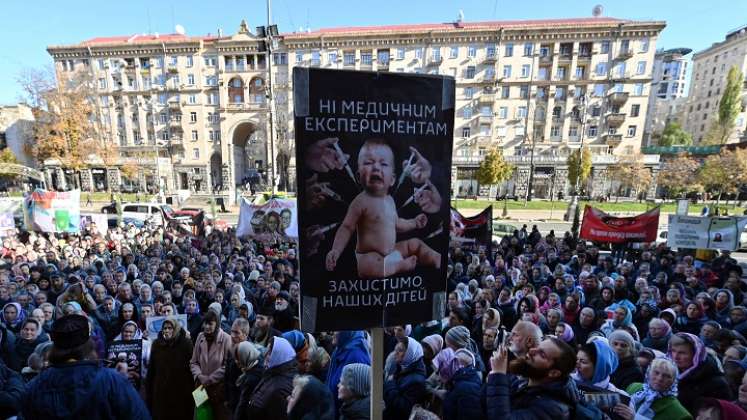 Los creyentes de la Iglesia Ortodoxa Ucraniana del Patriarcado de Moscú sostienen carteles que dicen "Sin experimentos médicos, proteja a nuestros niños" mientras realizan una manifestación frente a la oficina del alcalde. / AFP
