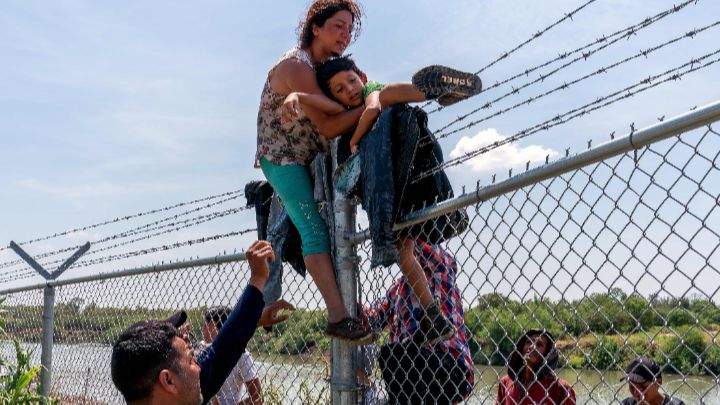 Estados Unidos-Migrantes trepan una valla de alambre de púas después de cruzar el Río Grande hacia norteamérica desde México, en Texas, el 25 de agosto.