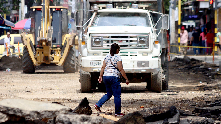 Una mujer camina en medio de la vía en reparación. 