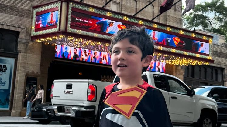 Entre afiches de la película que marcó su debut en el cine, el actor presume su camiseta de Superman y una sonrisa que delata su emoción.
