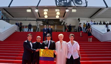 (De izquierda a derecha) El actor colombiano Juan Pablo Urrego, el director tailandés Apichatpong Weerasethakul, el actor colombiano Elkin Díaz, la actriz británica Tilda Swinton y la actriz francesa Jeanne Balibar posan con una bandera colombiana que dice "SOS" en apoyo a las protestas contra el gobierno en Colombia.