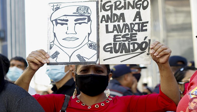 Un partidario del gobierno venezolano liderado por el presidente Nicolás Maduro sostiene una señal contra el líder opositor Juan Guaidó, frente a la Asamblea Nacional.