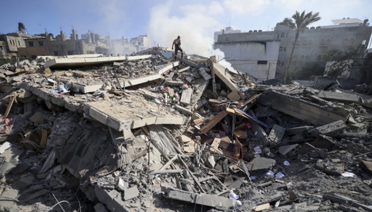 Un miembro de la defensa civil palestina camina entre los escombros de un edificio en la ciudad de Gaza que albergaba el Banco Intaj vinculado al movimiento Hamás que controla la Franja de Gaza. / Foto: AFP