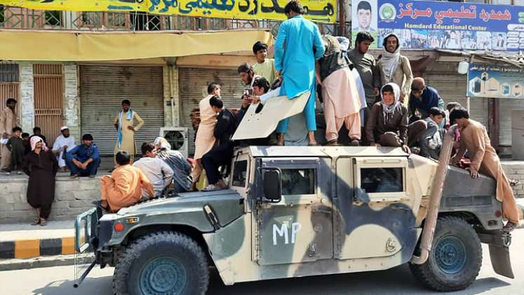 Los combatientes talibanes y los residentes locales se sientan sobre un vehículo Humvee del Ejército Nacional Afgano (ANA) a lo largo de la carretera en la provincia de Laghman el 15 de agosto de 2021. / Foto: AFP