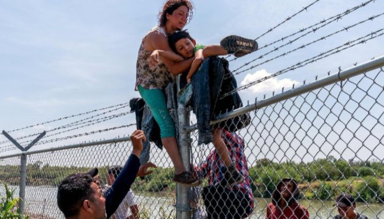 AFP Estados Unidos-Migrantes trepan una valla de alambre de púas después de cruzar el Río Grande hacia norteamérica desde México, en Texas, el 25 de agosto.
