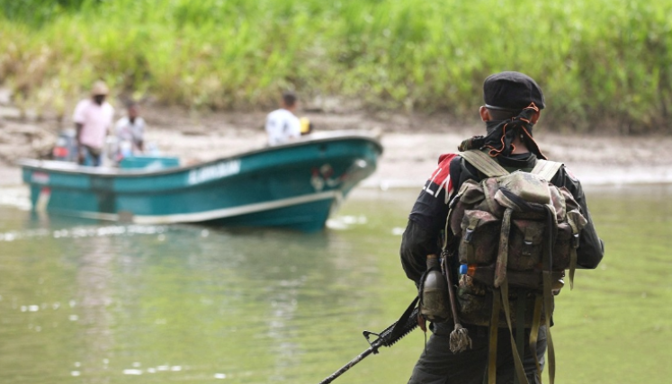 Guerrillero del Eln mira a un lanchero a la orilla del río en Colombia. 