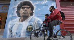 Un hombre pasa en bicicleta frente a un mural pintado por el artista Marley afuera del estadio Diego Armando Maradona. / Foto: AFP