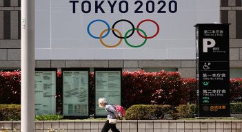 Una anciana pasa junto a una pancarta oficial de los Juegos Olímpicos de Tokio 2020 en el edificio del gobierno metropolitano de Tokio.