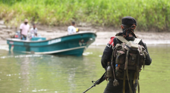 Guerrillero del Eln mira a un lanchero a la orilla del río en Colombia. 