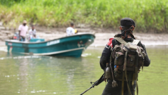 Guerrillero del Eln mira a un lanchero a la orilla del río en Colombia. 
