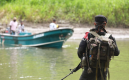 Guerrillero del Eln mira a un lanchero a la orilla del río en Colombia. 